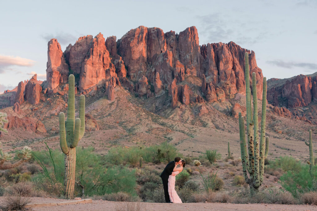 Engaged couple walking at Lost Dutchman Trail with the Superstition Mountains at sunset photographed by a Phoenix engagement photographer.