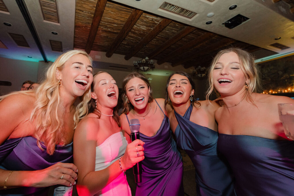 Candid photo of friends laughing together at a desert wedding reception.