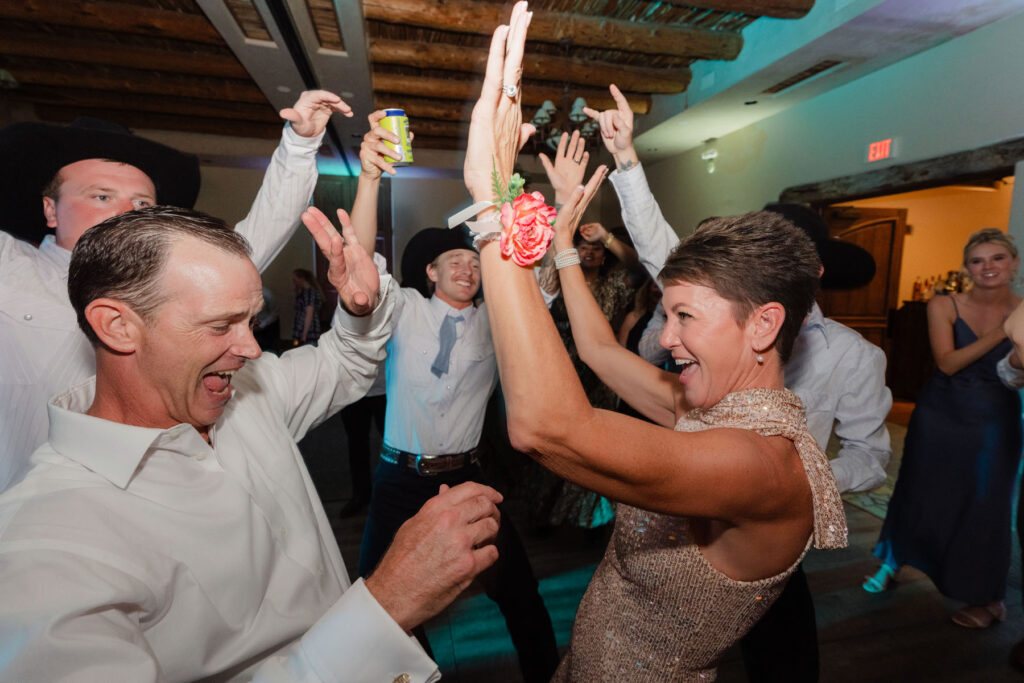 Bride and groom celebrating on the dance floor as guests cheer during their destination style Arizona wedding.