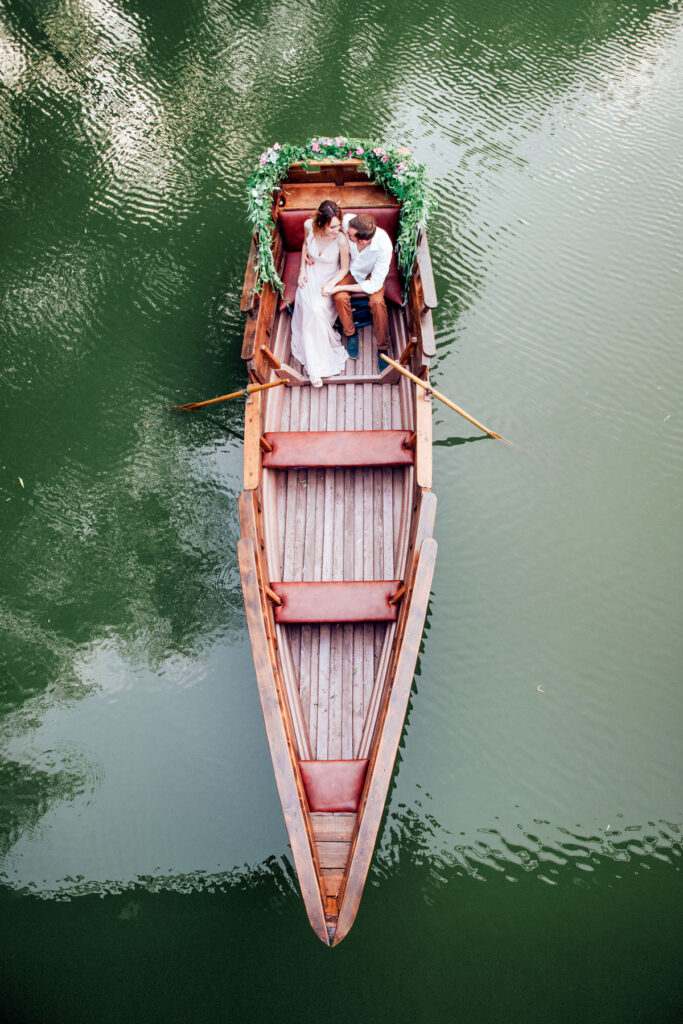 Bride & groom sitting on a boat for a drone portrait.