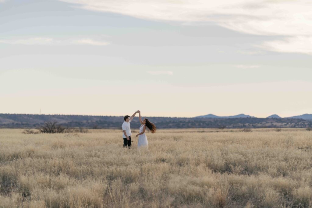 An engaged couple dances in a field during their Arizona engagement session on a warm summers' day.  