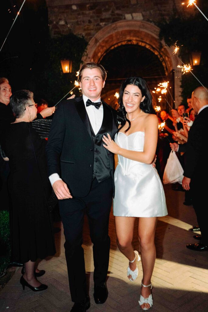 A bride and groom walk outside during their sparkler exit at Villa Siena.