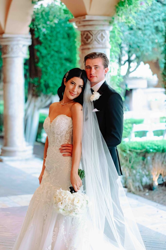 A bride and groom stand under the covered hallway along the courtyard at Villa Siena.